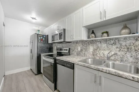 a kitchen with stainless steel appliances granite countertop a refrigerator and a sink
