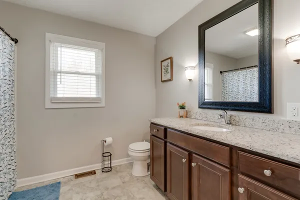 a bathroom with a granite countertop toilet sink and mirror