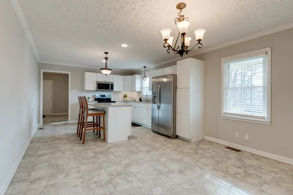 a view of a kitchen with a sink a refrigerator and a chandelier