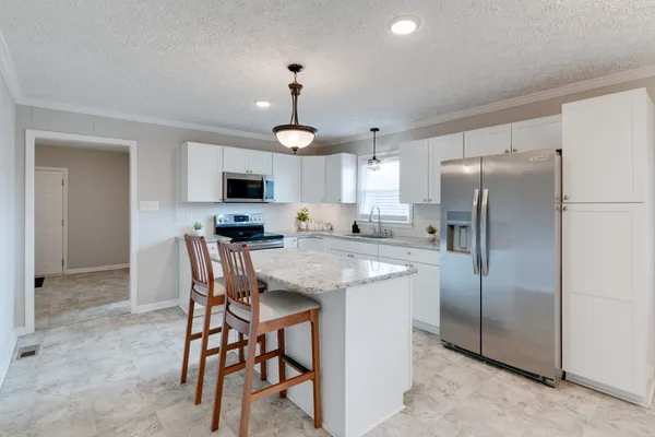 a kitchen with stainless steel appliances granite countertop a refrigerator a stove a microwave oven a sink with a dining table and chairs