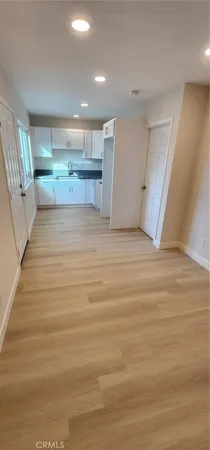 a view of kitchen and empty room with wooden floor