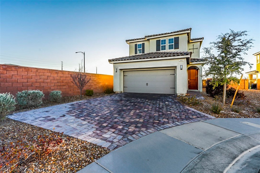 View of front of property with stucco siding, decorative driveway, and a garage