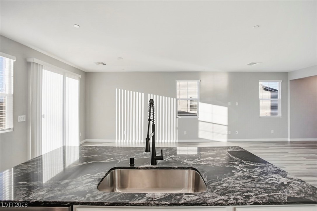 2865 Mincio Street Henderson, NV 89044 - Photo 30 of 33 Kitchen featuring dark stone counters, a center island with sink, open floor plan, and white cabinets