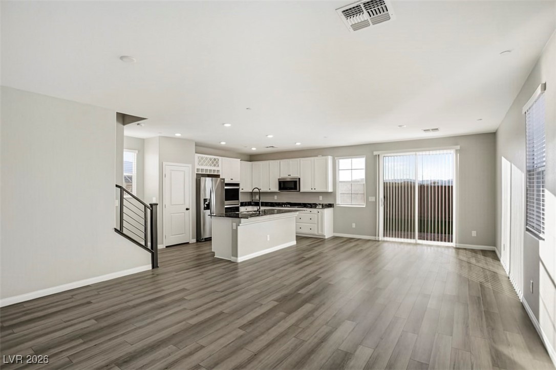 2865 Mincio Street Henderson, NV 89044 - Photo 27 of 33 Kitchen with open floor plan, white cabinets, dark countertops, an island with sink, and dark wood-style flooring