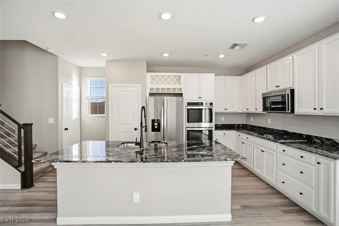 2865 Mincio Street Henderson, NV 89044 - Photo 6 of 33 Kitchen featuring dark stone countertops, stainless steel appliances, white cabinets, and recessed lighting