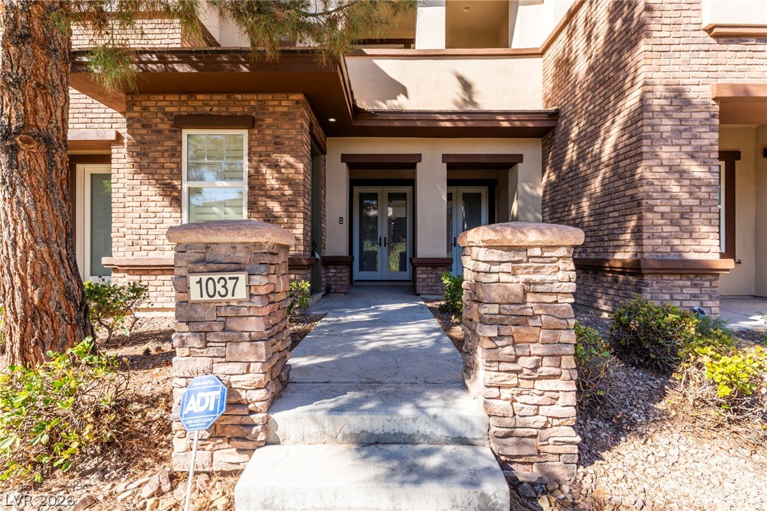 View of front entry with french doors, stucco siding, and brick siding