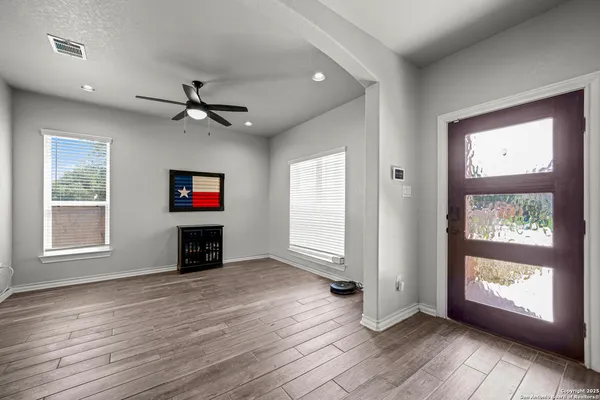 an empty room with windows a fireplace a ceiling fan and windows