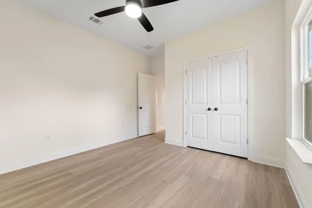 an empty room with wooden floor cabinet and windows