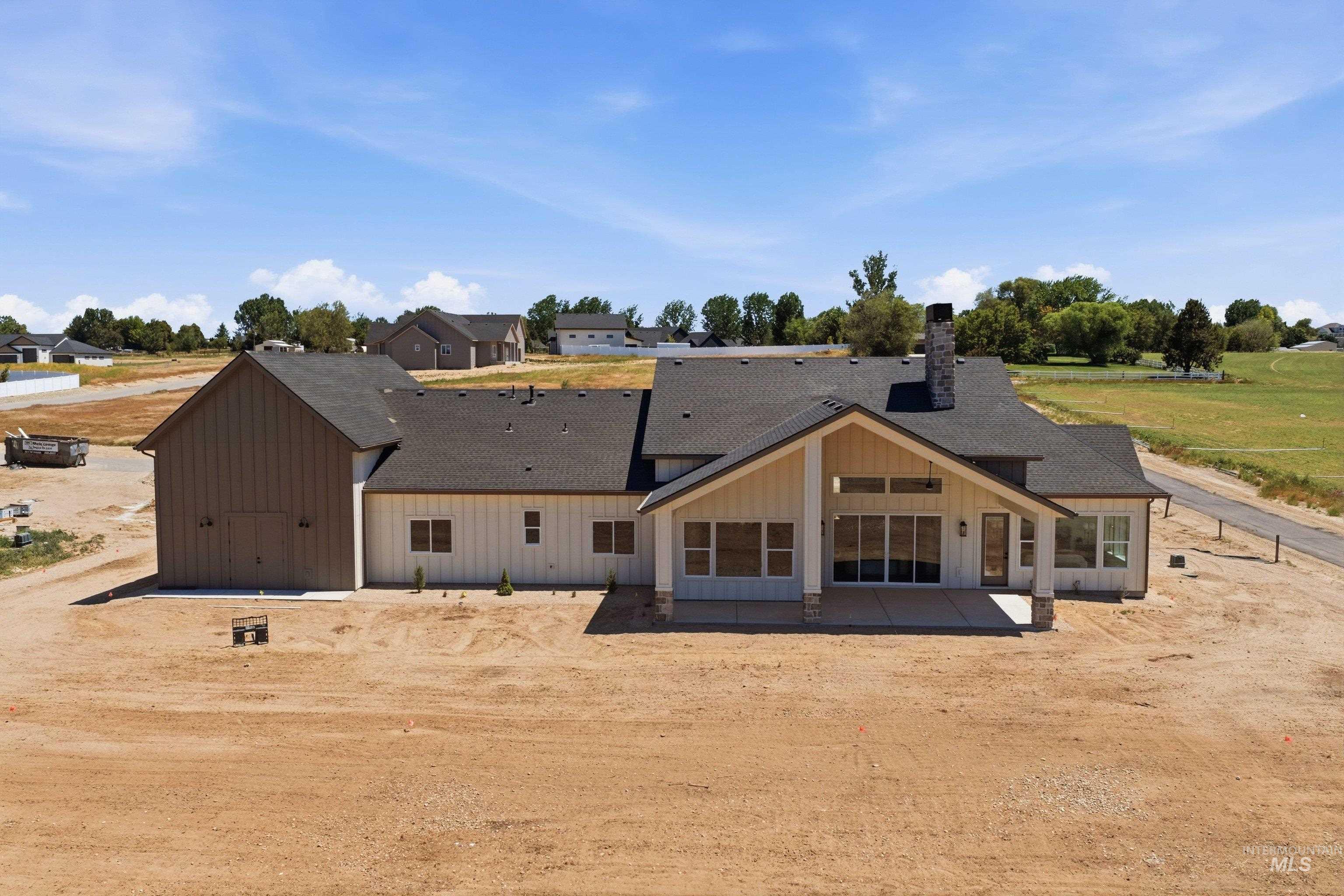 24763 Ardmore Court Caldwell, ID 83607 - Photo 44 of 50 New construction property featuring a large covered patio with stone columns, multiple large windows, a prominent gable roofline, and a stone chimney