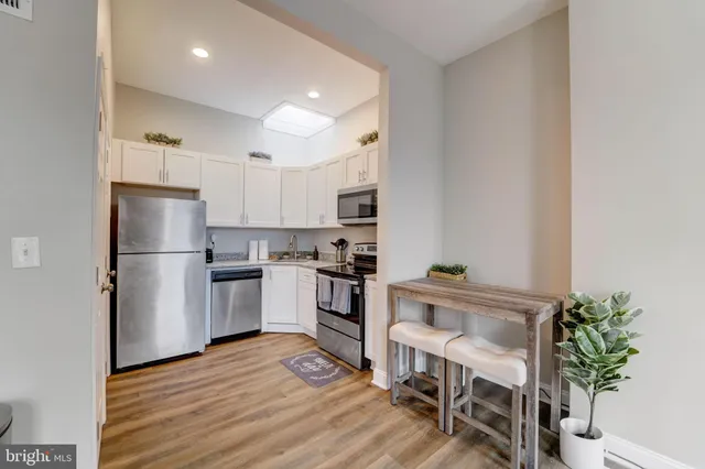 a white kitchen with granite countertop a refrigerator stove and microwave