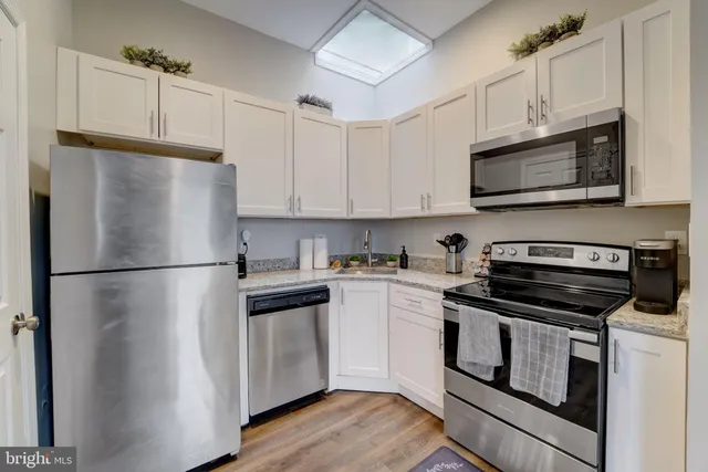 a kitchen with granite countertop a stove a microwave a sink and cabinets