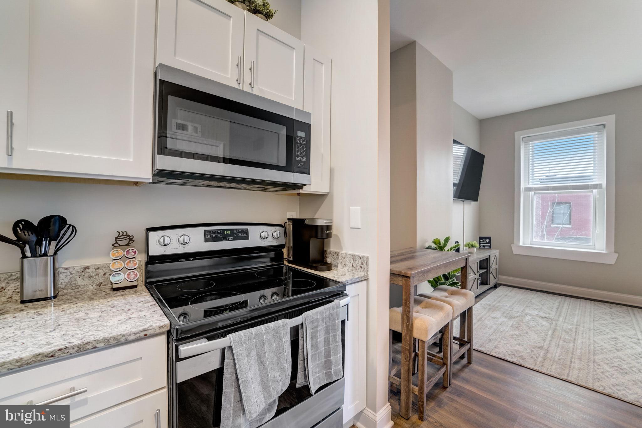1628 North Calvert Street Baltimore, MD 21202 - Photo 42 of 50 a kitchen with granite countertop a stove a microwave a sink and cabinets