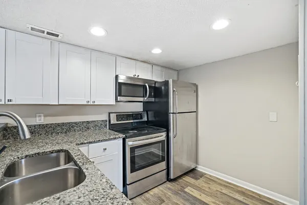 a kitchen with granite countertop a sink stainless steel appliances and cabinets