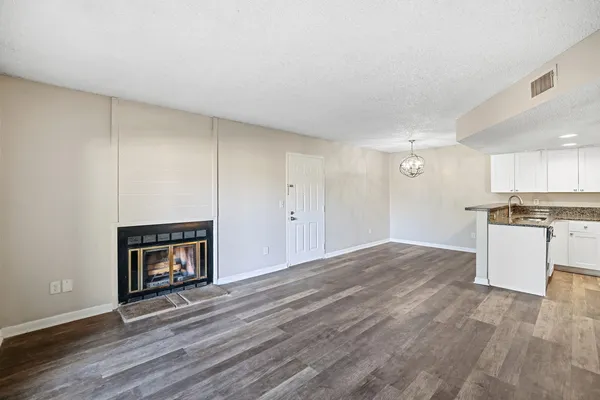 a view of empty room with wooden floor and kitchen