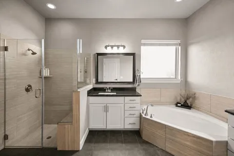 a bathroom with a granite countertop sink a mirror and a bathtub