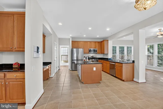 a kitchen with stainless steel appliances granite countertop a refrigerator a stove top oven and a sink