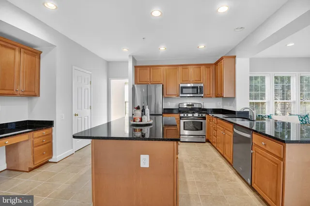 a large kitchen with stainless steel appliances granite countertop a stove a sink a refrigerator and a microwave