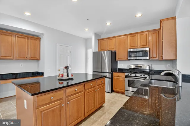a kitchen with granite countertop a sink a counter space appliances and cabinets