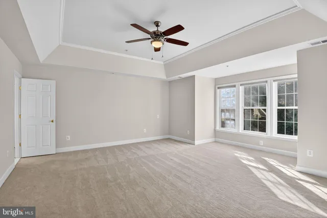 a view of an empty room with a ceiling fan and window