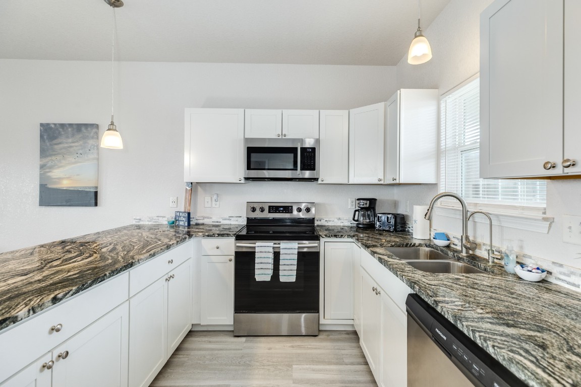 116 Howard Avenue, Unit G Surfside Beach, TX 77541 - Photo 10 of 31 a kitchen with stainless steel appliances granite countertop a stove sink and cabinets