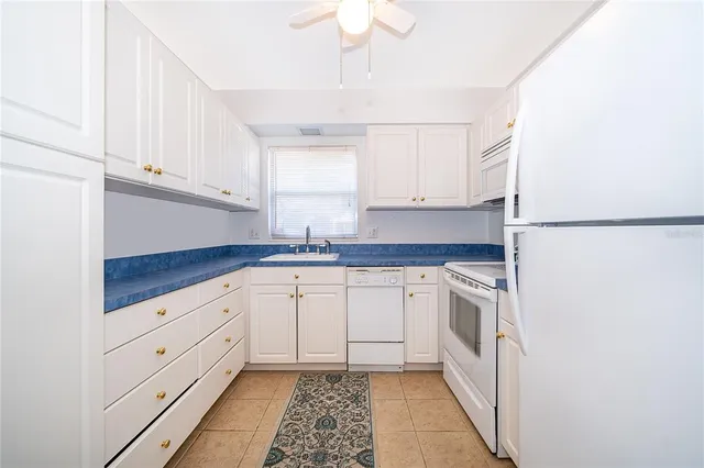 a kitchen with granite countertop white cabinets and white appliances