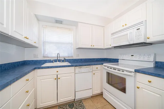 a kitchen with granite countertop white cabinets and white appliances