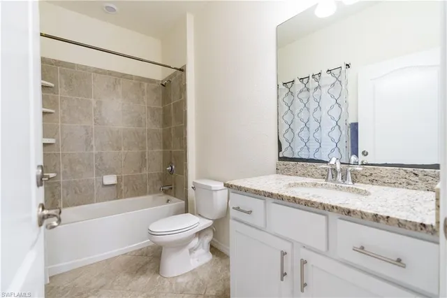 a bathroom with a granite countertop sink a toilet and shower