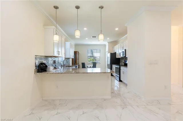 a view of a kitchen with kitchen island a stove a refrigerator a sink dishwasher with a fireplace and cabinets