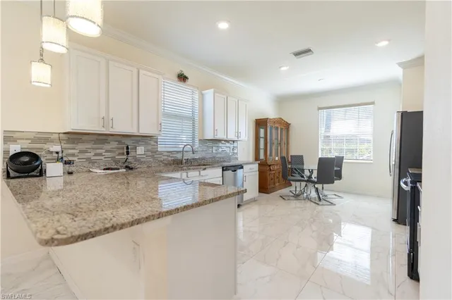 a view of a kitchen with kitchen island a counter top space cabinets a sink and appliances