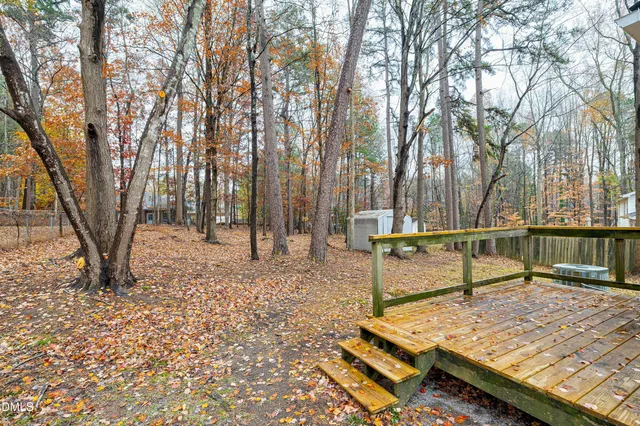a view of a backyard with wooden fence and a large tree