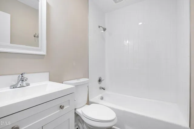 a bathroom with a bathtub shower sink vanity mirror and toilet