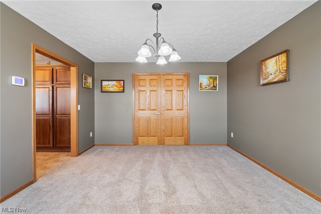 4363 Wile Road Wooster, OH 44691 - Photo 19 of 36 Unfurnished bedroom with a closet, an inviting chandelier, a textured ceiling, and light tile floors