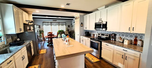 a kitchen with stainless steel appliances a sink a stove top oven a counter space and cabinets