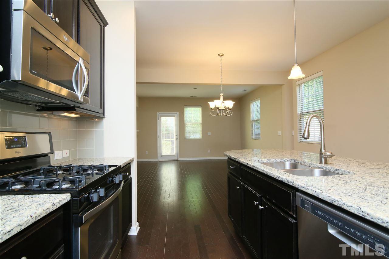 728 Wickham Ridge Road Apex, NC 27539 - Photo 7 of 21 a kitchen with granite countertop stainless steel appliances a sink stove and cabinets