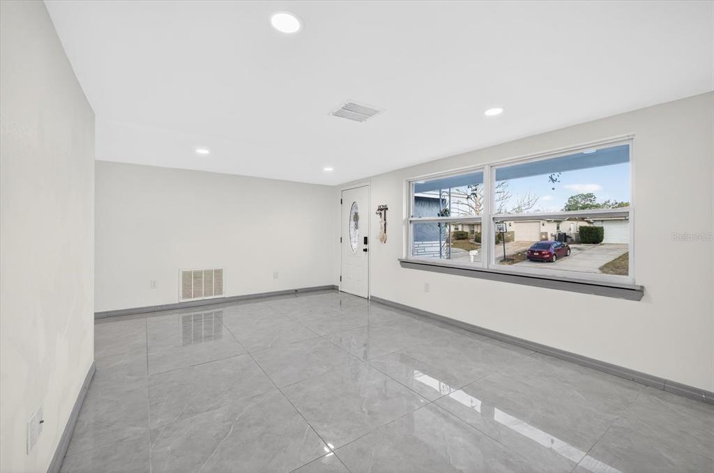 7814 Birchwood Drive Port Richey, FL 34668 - Photo 9 of 33 an empty room with chandelier fan and windows