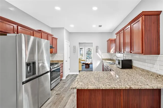 a kitchen with stainless steel appliances granite countertop a refrigerator a stove and a wooden cabinets