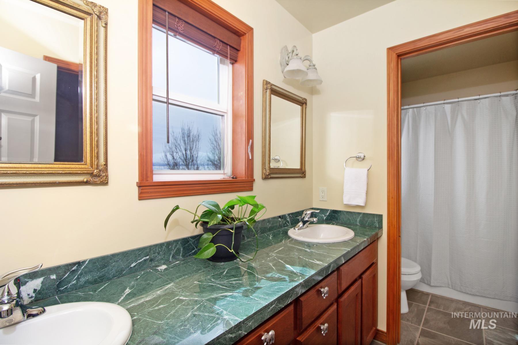 70 Tyler Drive Bellevue, ID 83313 - Photo 15 of 29 Bathroom with double vanity, curtained shower, and dark tile patterned flooring