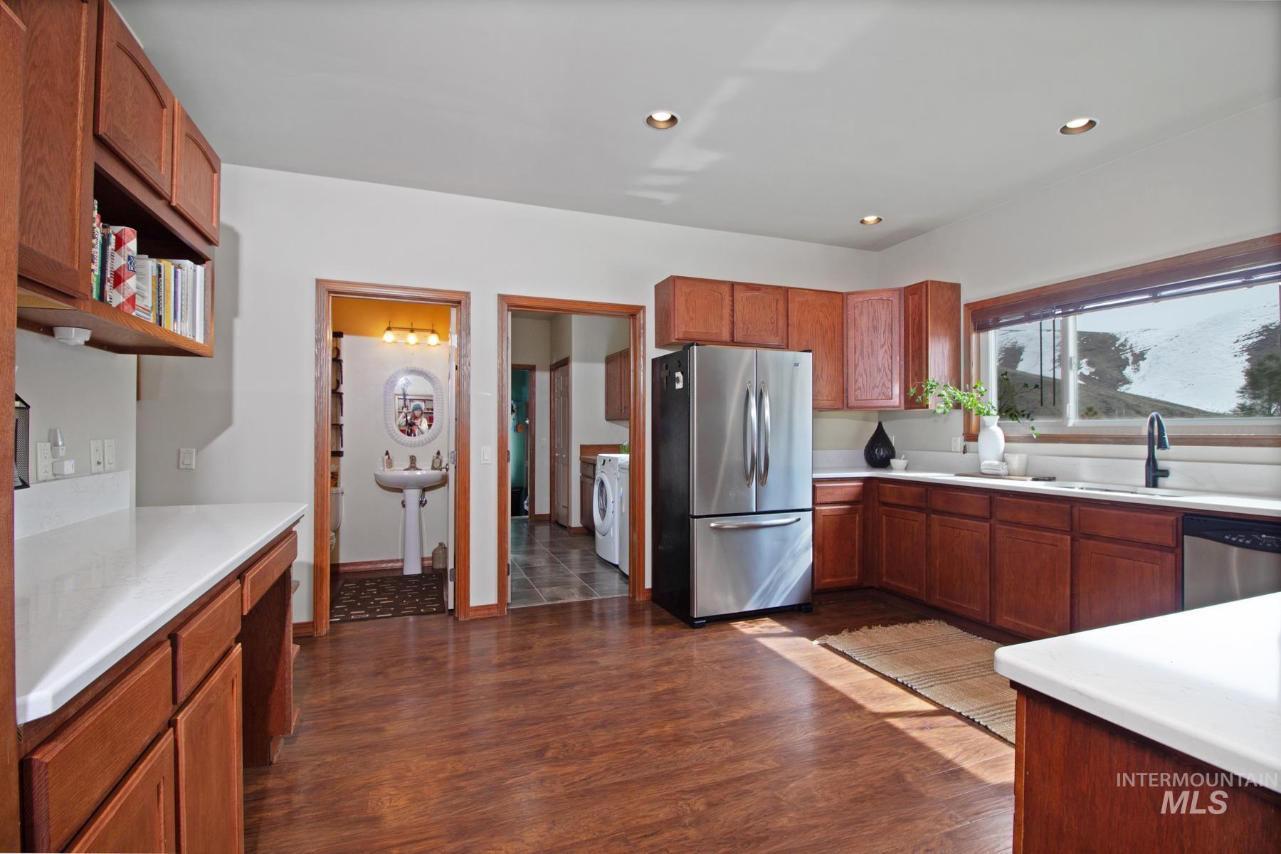 70 Tyler Drive Bellevue, ID 83313 - Photo 8 of 29 Kitchen with appliances with stainless steel finishes, light countertops, dark wood-style flooring, brown cabinetry, and recessed lighting