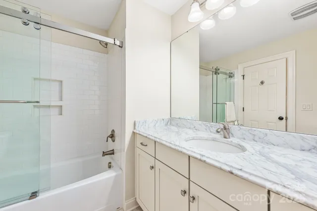 a bathroom with a granite countertop sink mirror and a bathtub