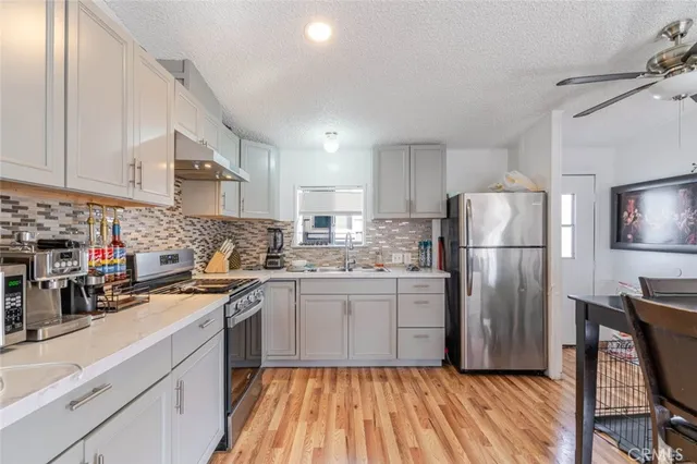 a kitchen with a refrigerator a sink dishwasher and a stove with wooden floor