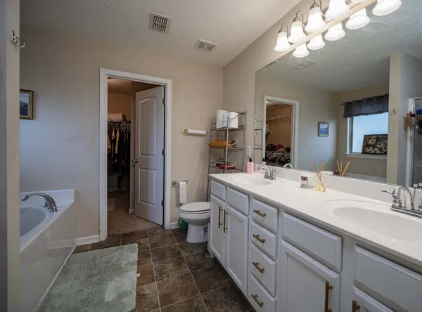 a spacious bathroom with a double vanity sink a large mirror and a toilet