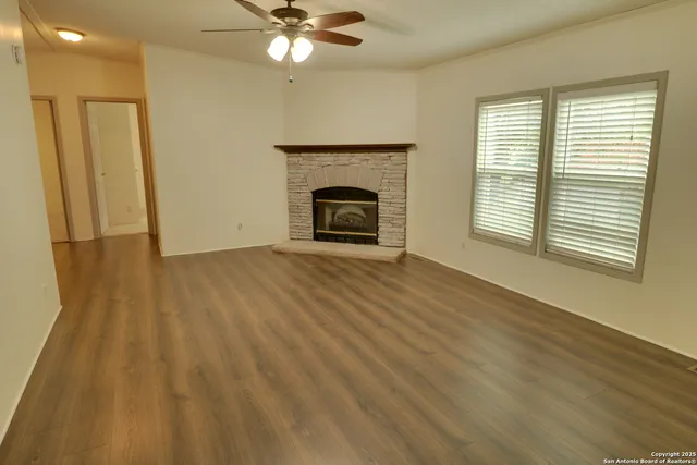 an empty room with wooden floor fireplace and windows
