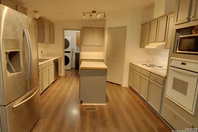 a kitchen with granite countertop a refrigerator a sink dishwasher and wooden cabinets with wooden floor