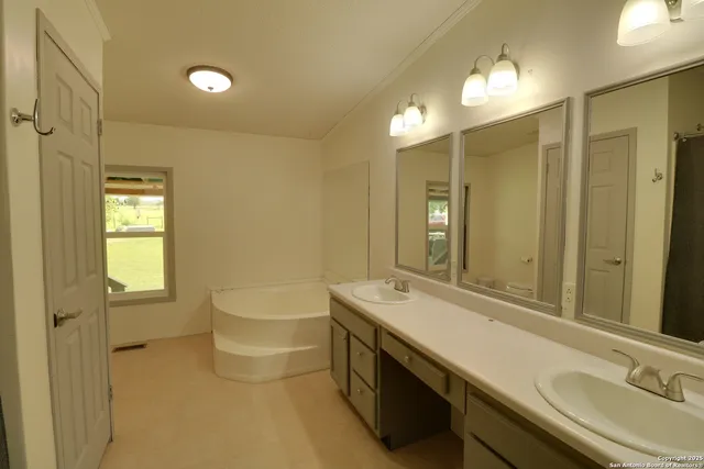 a bathroom with a double vanity sink mirror and bathtub