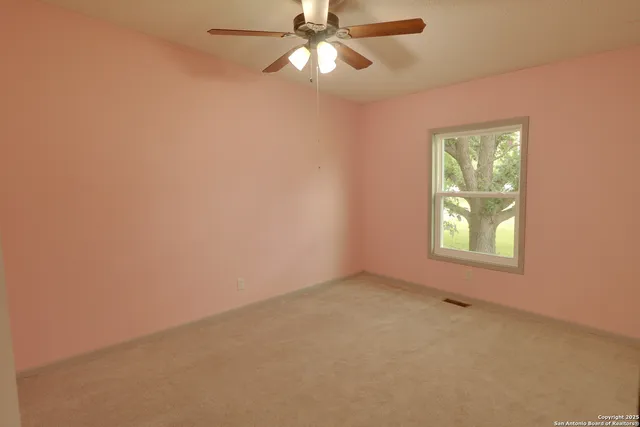 an empty room with a window and a fan