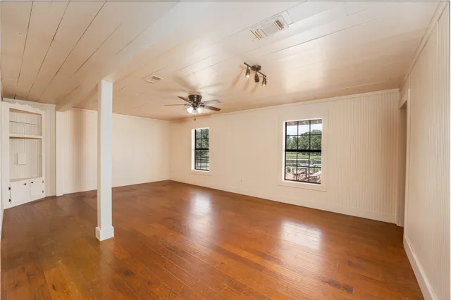 a view of an empty room with a window and wooden floor