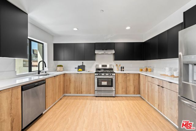 a kitchen with stainless steel appliances a stove top oven a sink and a refrigerator