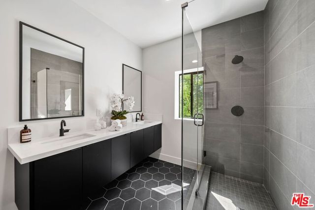 a bathroom with a double vanity sink mirror and shower
