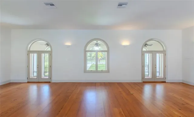 a view of an empty room with wooden floor and window with wooden floor