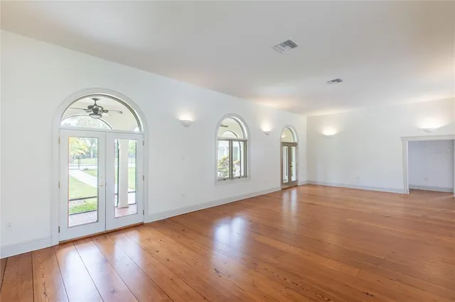 an empty room with wooden floor and windows